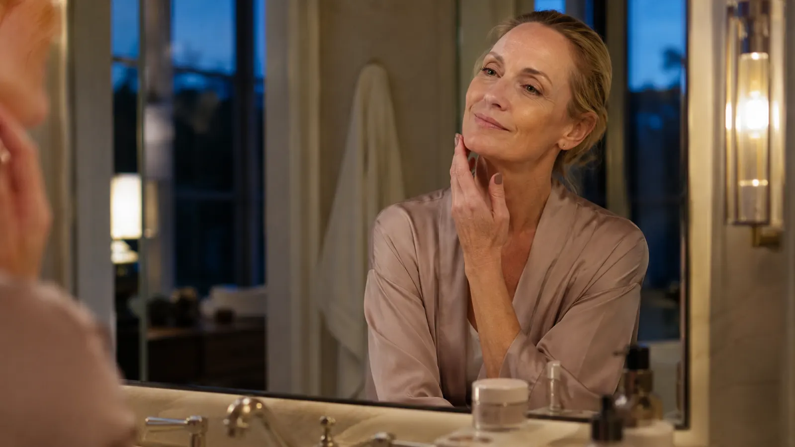 Woman relaxed at her bathroom counter after finishing her nightly neck cream routine, jar capped and set aside