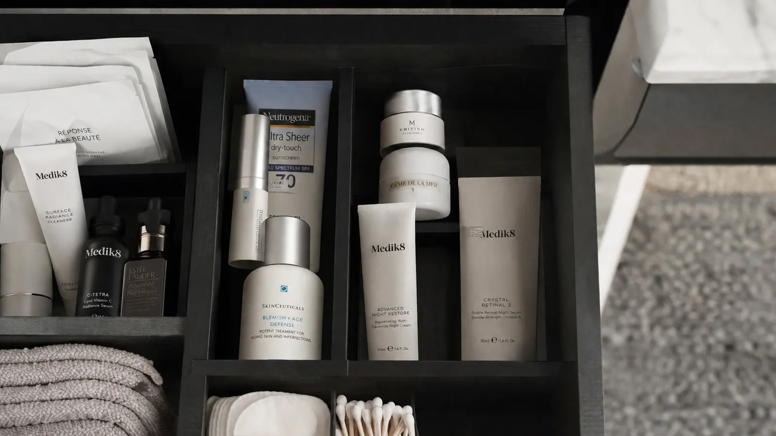 A tube of retinol cream stored upright in a cool, dark bathroom drawer alongside other skincare items