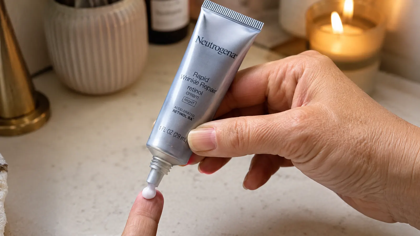 Hand squeezing a pea sized amount of Neutrogena Rapid Wrinkle Repair retinol cream from the tube onto a fingertip